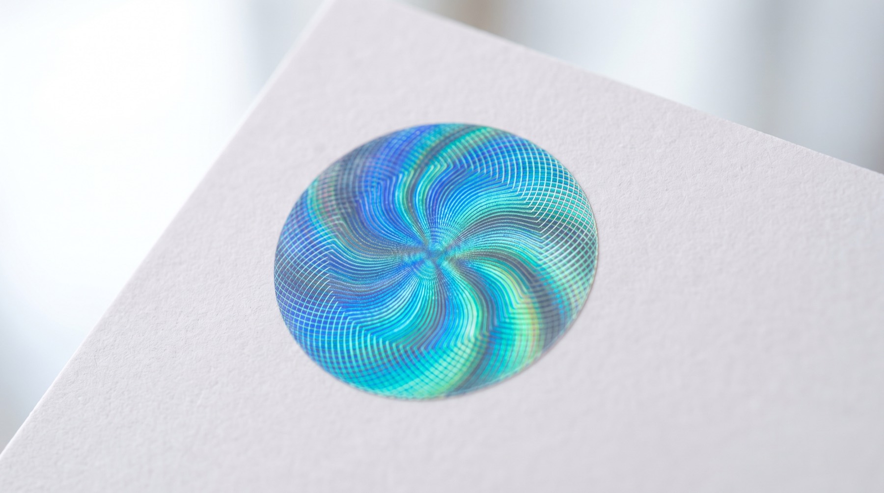An iridescent foil patch with a fine line pattern on plain white card